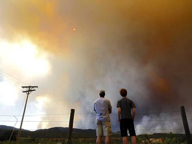 Robby Wood (L) of Denver, Colorado and his 16-year-old nephew Jacob Wood also of Denver, Colorado watch as smoke and flames encroach upon homes and ranches on the eastern front of the High Park Fire near Laporte, Colorado. The fire started on Saturday and was estimated at more than 14,000 acres on Sunday morning. At least 18 structures were lost or damaged due to the fire with more threatened and officials are searching for one person believed to be missing. The cause of the fire is unknown and it remains at zero percent containment. Reuters/Marc Piscotty