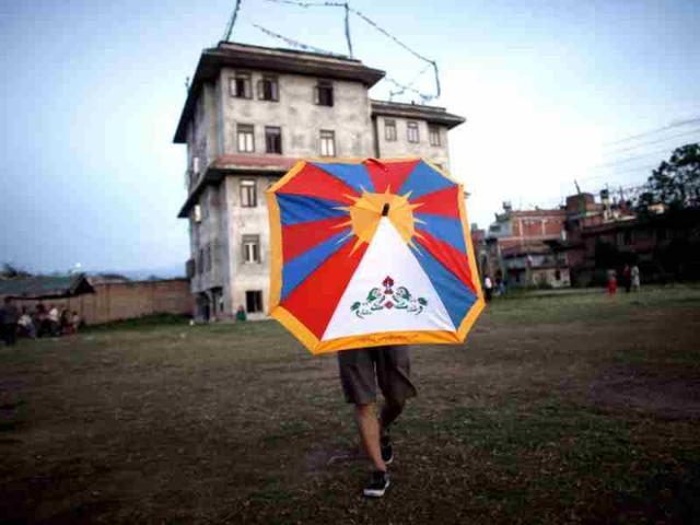 A Tibetan man holds an umbrella in the shape of Tibetan flag inside a Tibetan refugee camp, in Kathmandu. AP/Niranjan Shrestha