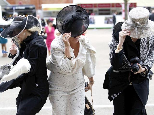 Race goers struggle to keep their hats on in strong winds on the fourth day at Royal Ascot, southwest of London. (Reuters/Andrew Winning)