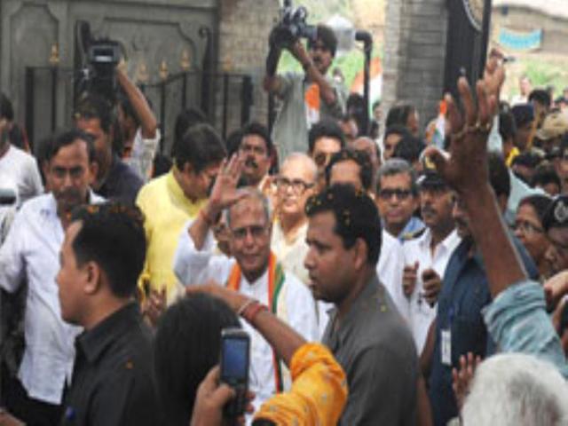 The Union finance minister and the ruling UPA candidate for the Presidential election Pranab Mukherjee surrounded by his family members and supporters gestures on his arrival at his ancestral house in Mirati village around 200km north west of Kolkata. (AFP photo/Dibyangshu Sarkar)