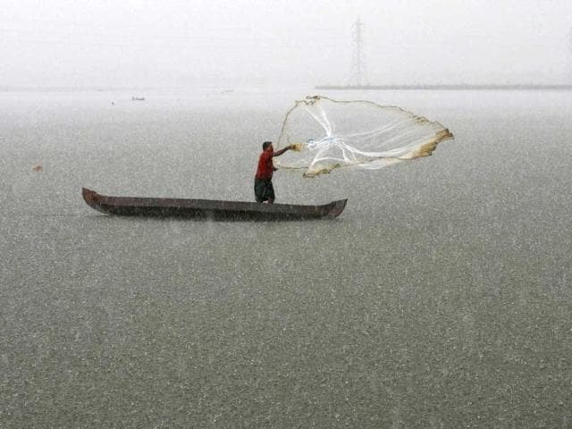 Man casts his fishing net into the waters of a fish farm during a heavy rain shower on the outskirts of Kochi. The India Meteorological Department (IMD) has forecast average rainfall for the whole June to September. Reuters/Sivaram V