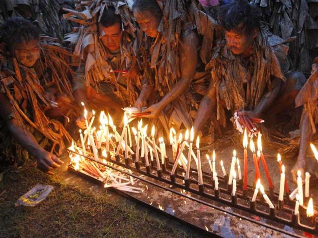 Devotees, covered with mud and dried banana leaves, light candles as they take part in a religious ceremony celebrating the feast day of their Catholic patron Saint John the Baptist in the village of Bibiclat, Nueva Ecija, north of Manila. Reuters/Erik De Castro