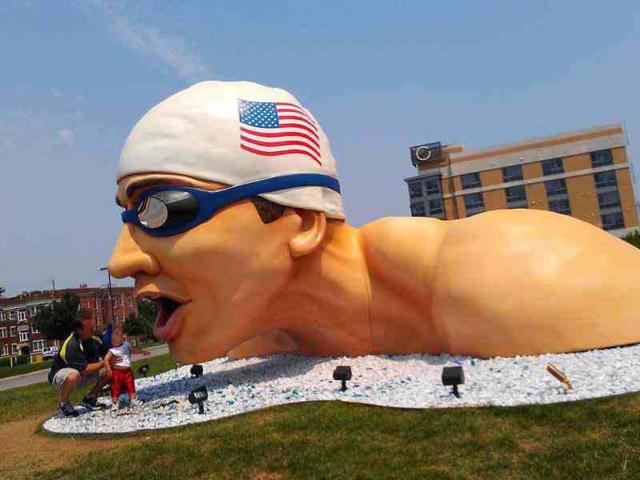Visitors inspect a giant statue of Michael Phelps in downtown Omaha during day 6 of the 2012 US Olympic Swimming Team Trials at Qwest Center in Omaha, heNebraska. AFP/Jamie Squire