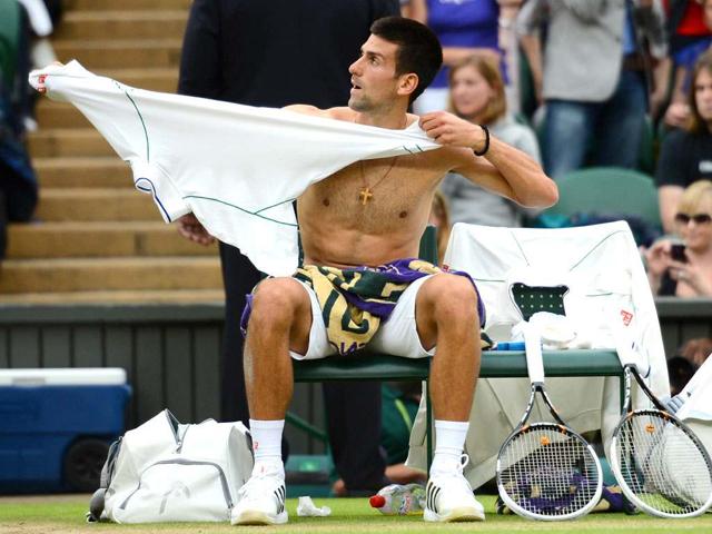 Serbia's Novak Djokovic changes his shirt during a break between games in his men's singles semi-final match against Switzerland's Roger Federer on day 11 of the 2012 Wimbledon Championships tennis tournament at the All England Tennis Club in Wimbledon. AFP/ Leon Neal