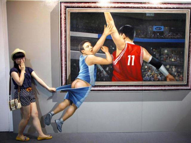 A girl poses for a photograph in front of a 3D painting at the 2012 Magic Art Special Exhibition in Hangzhou. Reuters/Carlos Barria