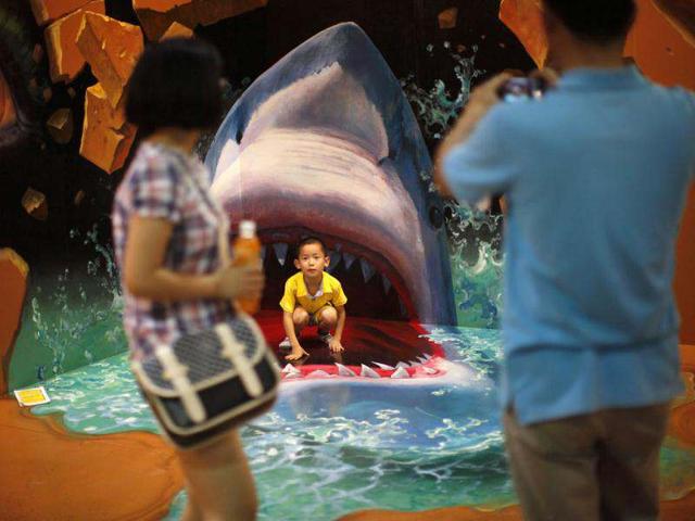 A boy poses for a photograph in front of a 3D painting at the 2012 Magic Art Special Exhibition in Hangzhou. Reuters/Carlos Barria
