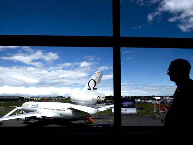A journalist looks at the Omega Tanker aircraft parked on the tarmac on the third day at the Farnborough International Airshow in Hampshire, southern England. Thousands of industry executives from the worlds of aerospace and defence are gathered at the biennial show. AFP Photo/Adrian Dennis