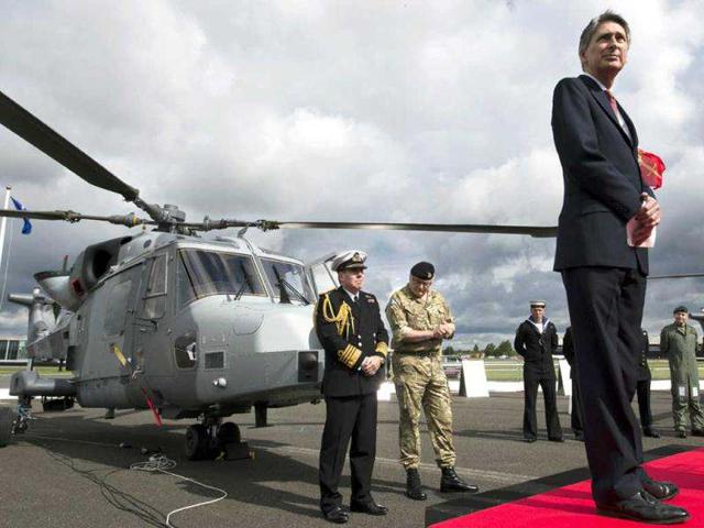 Secretary of State for Defence Philip Hammond (R) waits to give a speech while First Sea Lord Admiral Mark Stanhope (L) and Chief of General Staff Peter Wall (2nd L) look on beside a new AgustaWestland AW159 Wildcat helicopter at the Farnborough International Airshow in Hampshire, southern England. AFP Photo/Adrian Dennis