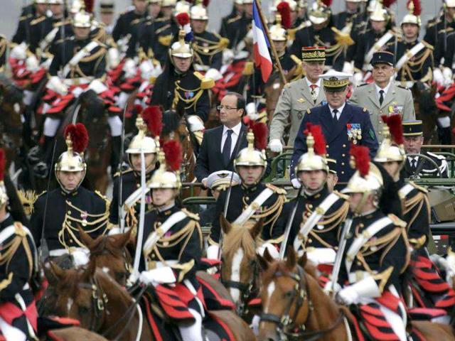 France's President Francois Hollande stands at attention in the command car as he reviews the troops while descending the Champs Elysees in Paris at the start of the traditional Bastille Day military parade in Paris. Reuters/Mal Langsdon