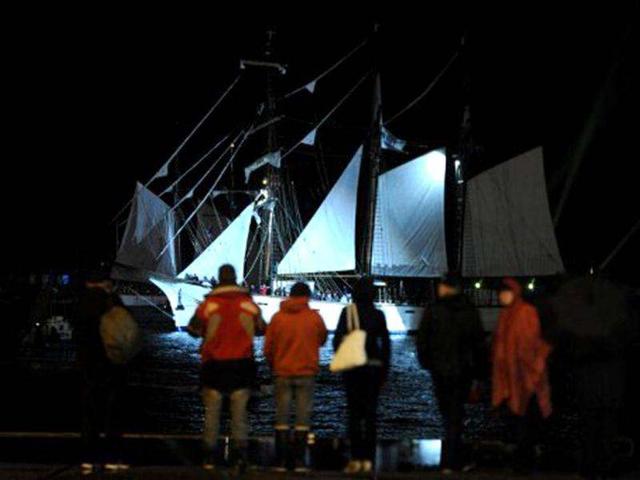 People look at Traditional sailboats sailing in Brest seaport as part of the 2012 Tonnerres de Brest maritime festival which features thousands of traditional sailboats. (AFP Photo/Alain Jocard)