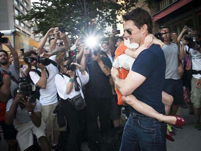 Tom Cruise walks by with daughter Suri as the paparazzi clicks them.