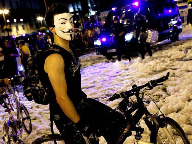 A demonstrator wearing a Guy Fawkes mask stands near Spanish National Police officers in full riot gear after a protest against government austerity measures in central Madrid. Reuters photo/Susana Vera