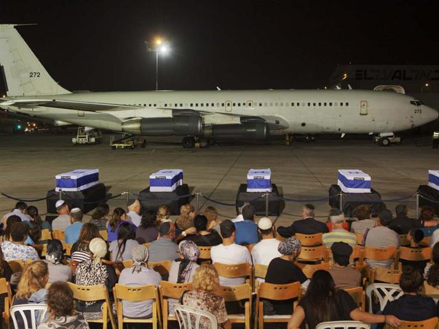 Relatives sit in front of the coffins of people killed in bombing in Bulgaria after the remains arrived at Tel Aviv airport, Israel. AP/Dan Balilty