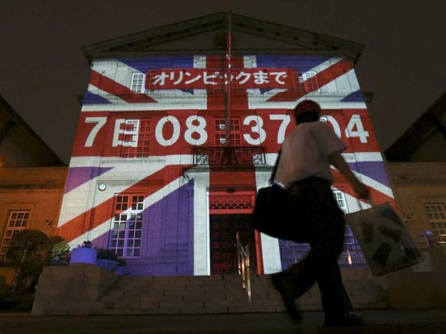 A man walks past a building, projecting a countdown clock to the opening of the London 2012 Olympic Games, at the British Embassy in Tokyo July 20, 2012. The lighting up with the Unicon flag together with the numbers of days, hours, minutes and seconds to go until the opening of the Olympic Games was projected on the front exterior of the Embassy's main building on Friday. The countdown will go until the actual time of the opening ceremony of the London 2012 Olympic Games. Reuters/Kim Kyung-Hoon