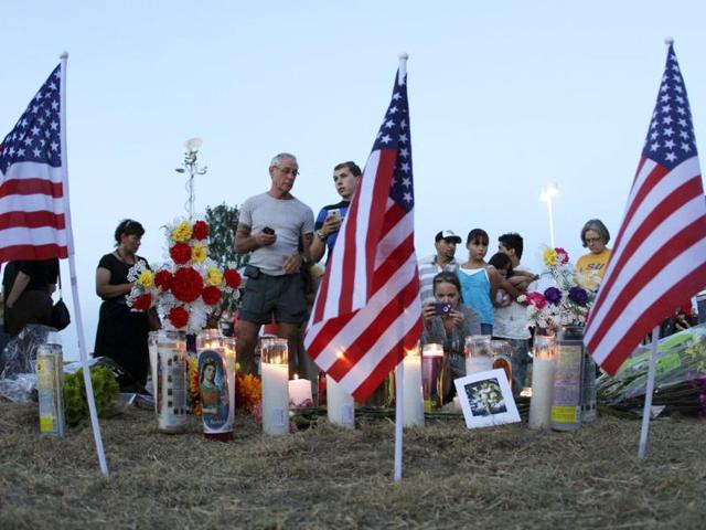 People attending a candle-light prayer gathering gather near a a group of candles and US flags in Aurora, Colorado. (AP Photo/Ted S. Warren)