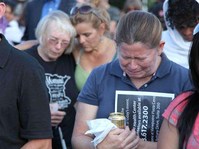 People mourn at a vigil in Aurora, Colorado. Authorities report that 12 died and more than three dozen people were shot during an assault at the theatre during a midnight premiere of "The Dark Knight." (AP Photo/Robert Ray)