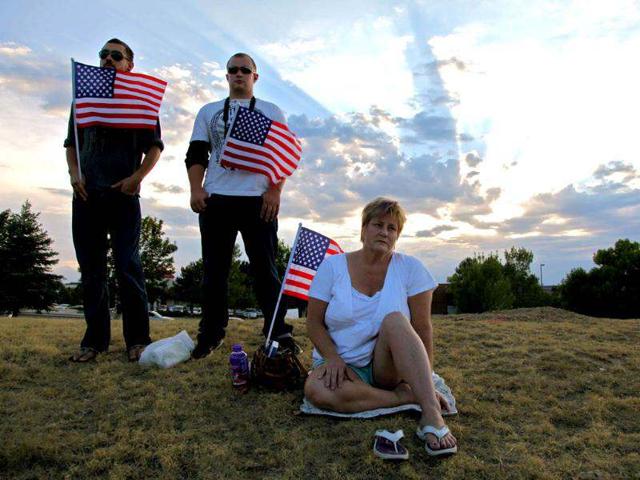 People hold American flags at a vigil in Aurora, Colorado. Authorities report that 12 died and more than three dozen people were shot during an assault at the theatre during a midnight premiere of "The Dark Knight." (AP Photo/Robert Ray)