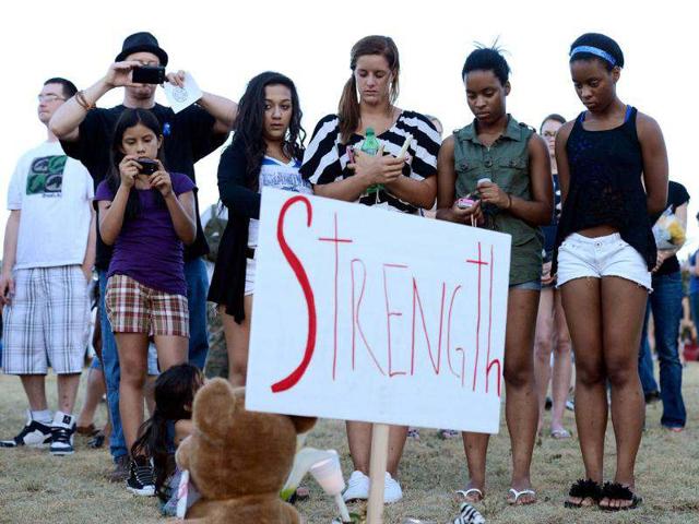 A group of teenagers pray during a vigil for victims at the Century 16 movie theatre where a gunmen attacked movie goers during an early morning screening of the new Batman movie, "The Dark Knight Rises" in Aurora, outside of Denver, Colorado. (Kevork Djansezian/Getty Images/AFP)