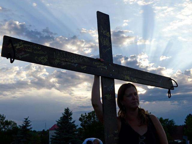 A woman holds a large cross during a vigil for victims at the Century 16 movie theatre where a gunmen attacked movie goers during an early morning screening of the new Batman movie, "The Dark Knight Rises" in Aurora, outside of Denver, Colorado. (Kevork Djansezian/Getty Images/AFP)
