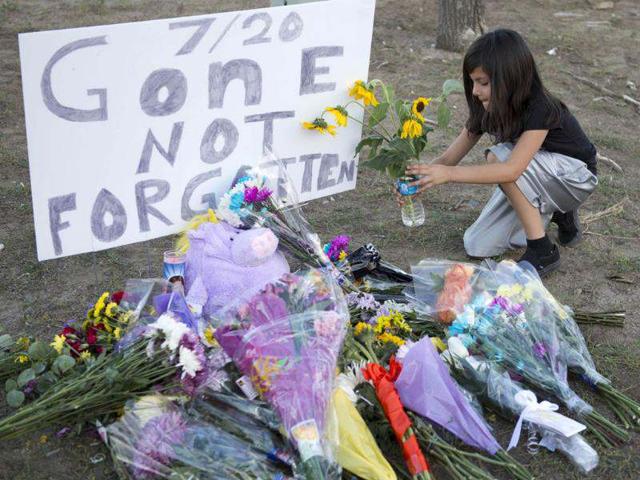 A girl leaves flowers at a memorial near theater where 12 people were killed in Aurora, Colorado. (AFP photo/Don Emmert)