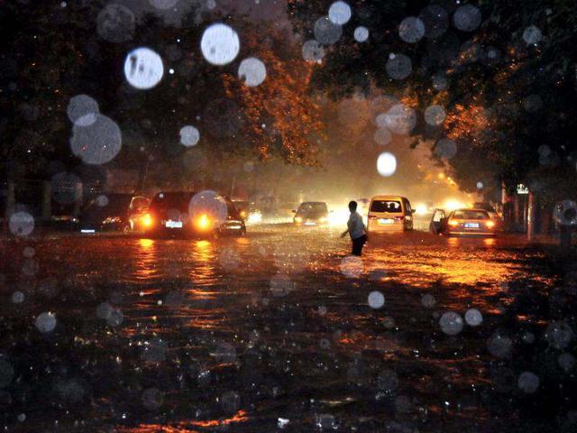 A woman wades through a flooded street following a heavy rain in Beijing. (AP Photo)