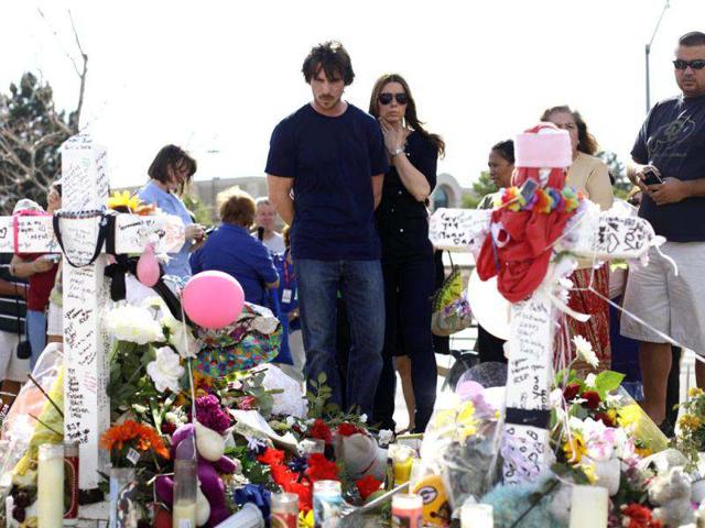 Actor Christian Bale and his wife Sibi Blazic look at the memorial to the victims of Friday's mass shooting, Tuesday, July 24, 2012, in Aurora, Colo. Twelve people were killed when a gunman opened fire during a late-night showing of the movie The Dark Knight Rises, which stars Bale as Batman.