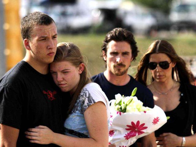A couple embraces each other as actor Christian Bale holds flowers before placing them at the memorial across the street from the Century 16 movie theater in Aurora, Colorado. The memorial was created for the victims of the mass shooting that occured at the theater last Friday.