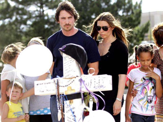 Actor Christian Bale and his wife Sandra Blazic look at the flowers and cards at the memorial across the street from the Century 16 movie theater.