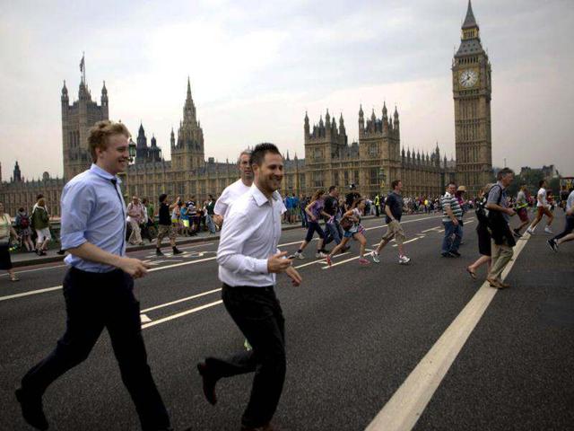 People cross the Westminster bridge to watch the royal barge Gloriana carry the Olympic flame along the river Thames, ahead of the 2012 Summer Olympics, on the final day of the Torch Relay, in London. (AP Photo/Emilio Morenatti)