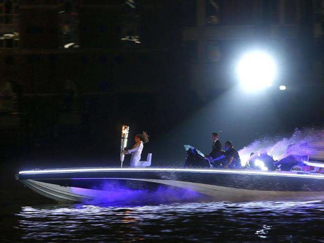 Britain's David Beckham (C) drives a powerboat with the Olympic torch as fireworks are launched over Tower Bridge during the opening ceremony of the London 2012 Olympic Games. (Reuters/Eddie Keogh)