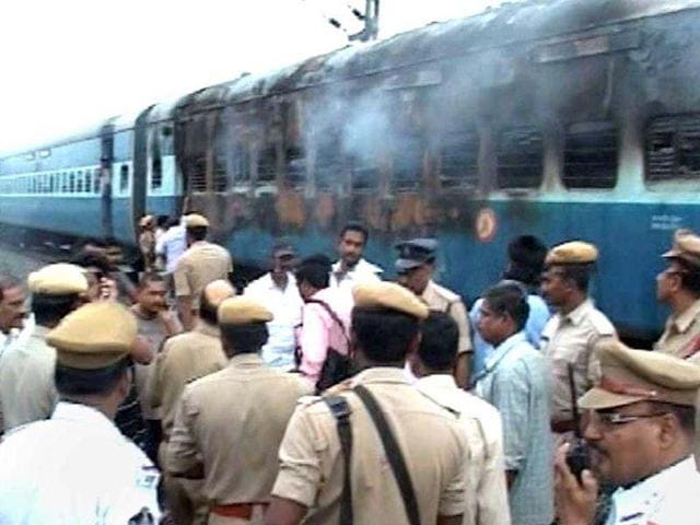 This video grab shows officials and rescue personnel inspecting the scene as smoke continues to smolder from a burnt out rail car after a fire ripped through a coach on a speeding express train near the town of Nellore. AFP Photo