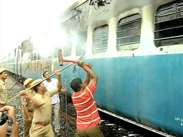 This video grab shows officials and rescue personnel trying to break into the car as smoke continues to smolder from the burnt out rail carriage after a fire ripped through a coach on a speeding express train near the town of Nellore. AFP Photo