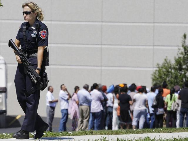 Police stand guard as bystanders watch at the scene of a shooting inside a Sikh temple in Oak Creek. (AP Photo)