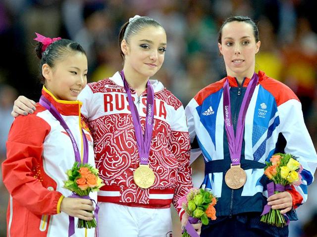 Gold medalist Russia's gymnast Aliya Mustafina (C), silver medalist China's He Kexin (L) and bronze medalist Britain's Beth Tweddle celebrate on the podium of the women's uneven bars of the artistic gymnastics event of the London Olympic Games on at the 02 North Greenwich Arena in London. (AFP photo/Ben Stansall)