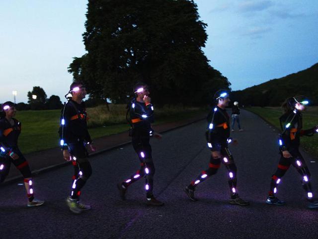 Runners taking part in NVA's Speed of Light walk across a path before taking part in the performance on Arthurs Seat during the Edinburgh International Festival in Edinburgh. Reuters photo