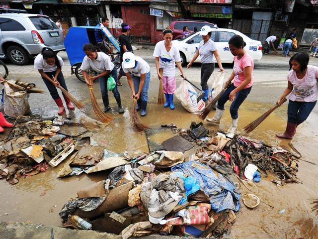 Volunteers sweep debris washed ashore during severe flooding in the village of Tumana, Marikina town, suburban Manila days after torrential rains inundated most of the capital affecting millions of residents. AFP/Ted Aljibe