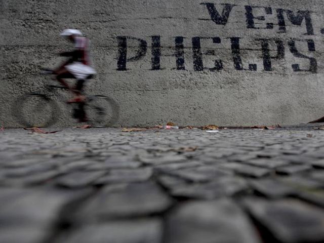 A man rides his bike past graffiti that reads 'Come on Phelps' in Rio de Janeiro. The world looks ahead to Rio de Janeiro and Brazil who will host the 2016 Olympic Games. (Reuters)
