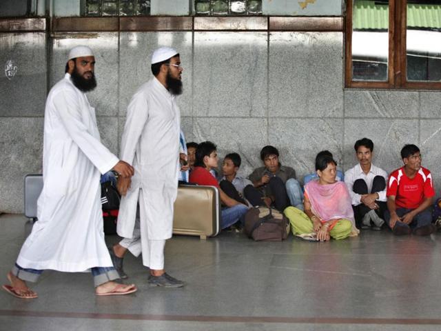Muslims walk past people from India's northeastern states waiting to board trains to go back home, at a train station in Bangalore. AP Photo