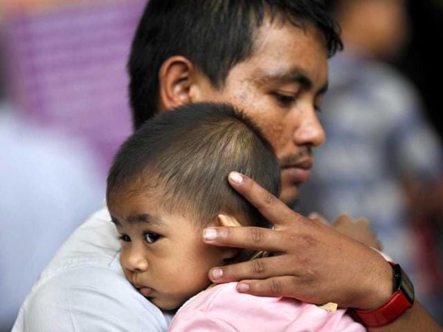 A northeastern man holds a child as they wait to board a train to head home, at a railway station in Bangalore. AP/Aijaz Rahi