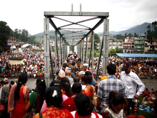 Hindu devotees cross a bridge over the Bagmati River to perform religious rituals on the banks of the Bagmati River while celebrating Kuse Aunse (Father's Day) at Gokarna Temple in Kathmandu. Hindus all over the country, whose fathers have passed away, come to the temple for worship, holy dips, and to present offerings. (Reuters)