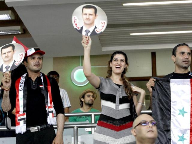 Syrians hold photographs of Syrian President Bashar al-Assad and cheer their team during an India vs Syria soccer match at the Nehru Cup International Football tournament, in New Delhi. AP/Manish Swarup