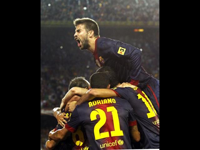 FC Barcelona's Gerard Pique, top, celebrates Andres Iniesta's, goal with team mates during a Spanish Supercup first leg soccer match against Real Madrid at the Camp Nou stadium in Barcelona, Spain. (AP Photo)