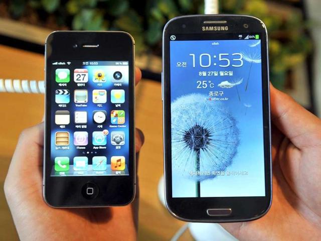 An-employee-shows-an-Apple-s-iPhone-4s-L-and-a-Samsung-s-Galaxy-S3-R-at-a-mobile-phone-shop-in-Seoul-Shares-in-Samsung-Electronics-opened-6-75-lower-after-a-US-court-fined-the-South-Korean-firm-1-05-billion-for-breaching-Apple-s-patents--AFP-photo-Jung-Yeon-Je