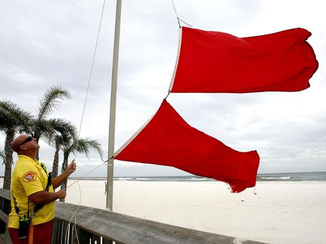 Scott Smothers, a lifeguard with the Gulf Shores Beach Patrol changes the warning flag to double red flags closing the waters at the Gulf Shores Public Beach as Tropical Storm Isaac approaches the Gulf Coast, Alabama. AP/John David Mercer