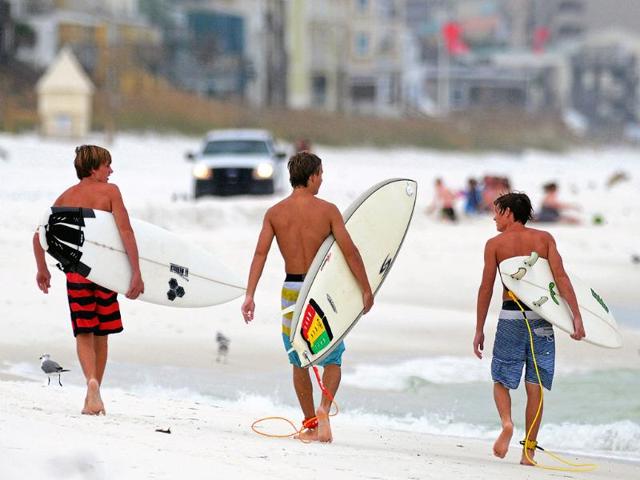 Local surfers walk down the beach in Destin, Florida. AP/Jeff Gammons
