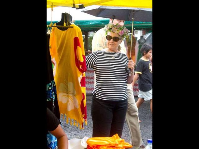 US Secretary of State Hillary Clinton looks at clothing during a visit to the Avarua markets in Rarotonga, Cook Islands. AFP PHOTO / Marty Melville