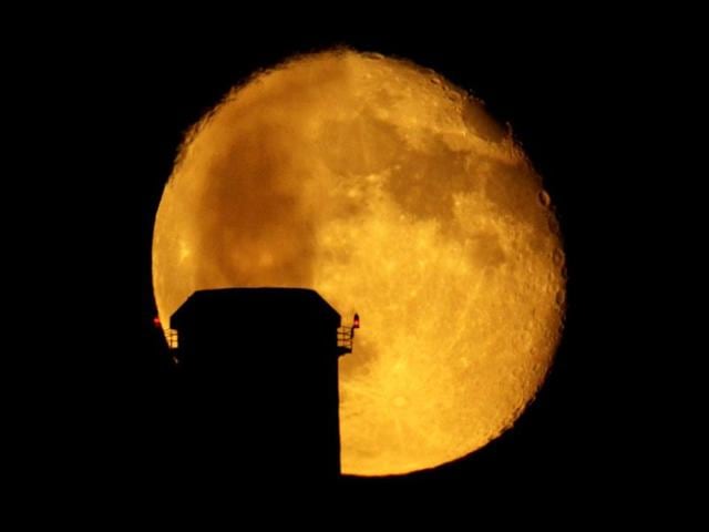 Emissions spewing from a smokestack at the La Cygne Power Plant are silhouetted against the rising moon in La Cygne, Kan. AP Photo/Charlie Riedel