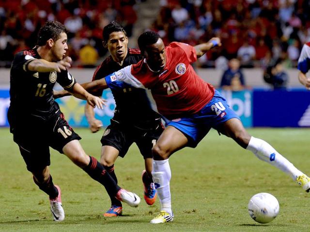 Costa Rica's Rodney Wallace is marked by Mexico's Israel Jimenez and Javier Aquino during their Brazil 2014 FIFA World Cup 2014 qualifier football match held at the National Stadium in San Jose. AFP/Ezequiel Becerra