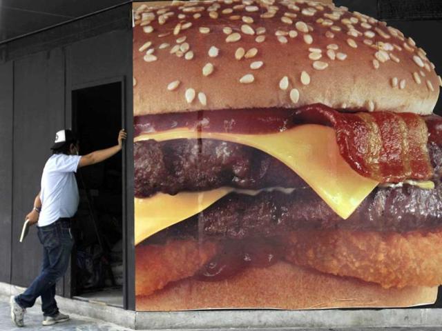 A Thai worker stands outside a new hamburger shop during its renovation in Bangkok. (AP Photo/Sakchai Lalit)