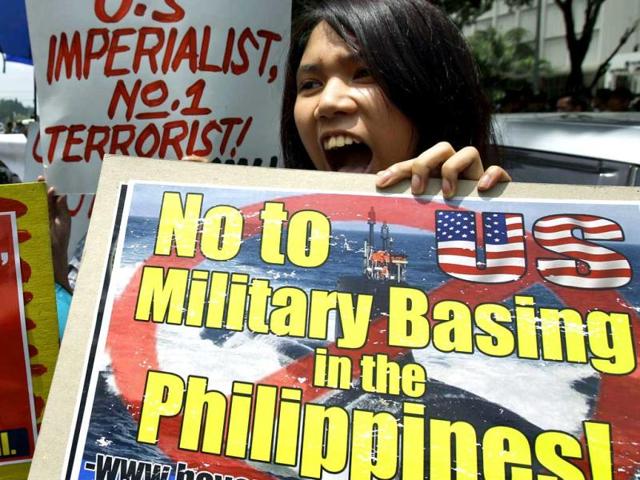 A Filipino activist holds a sign during a protest near the US Embassy in Manila, Philippines. The activists are condemning the presence of US troops in the Philippines. (AP Photo/Aaron Favila)
